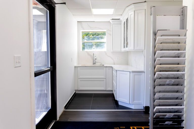 Bright white kitchen with black floor, cabinets, window, and stacked metal trays on the right