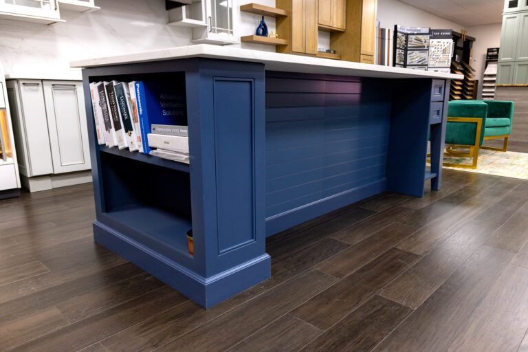 Blue library desk with books on a shelf, in a room with dark wood flooring