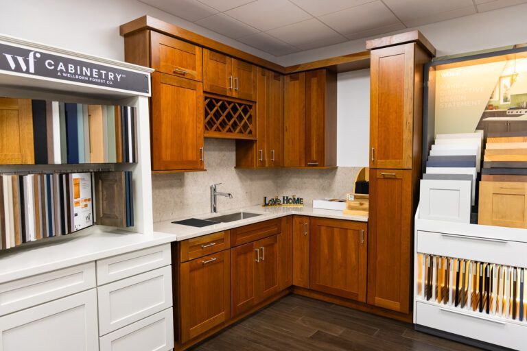 Wooden kitchen showroom with white cabinets, countertops, and display shelves of binders and samples