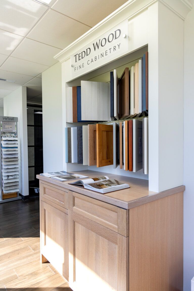 Wood floor sample display in a bright showroom with labeled panels and a wooden cabinet
