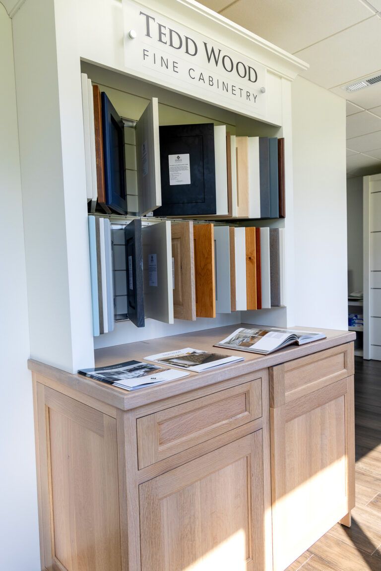 Display of fabric swatches and samples in a wooden showroom cabinet labeled “Tedd Wood”
