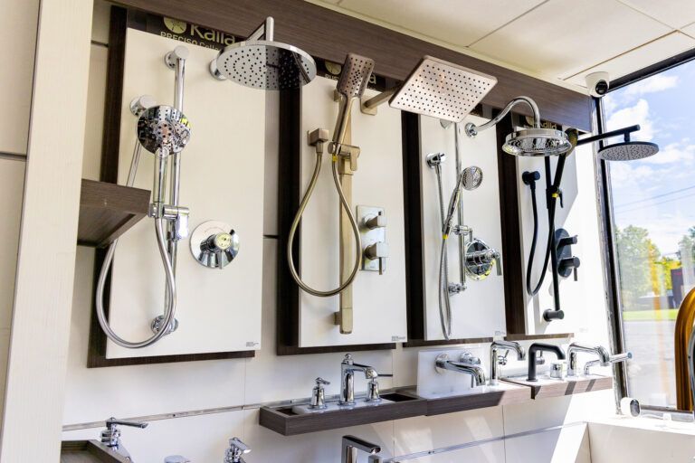Row of modern shower fixtures and sinks in a bright bathroom showroom