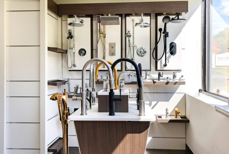 Modern kitchen with white countertops, brass faucets, and a wall of mirrors over the sink area.