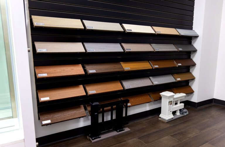 Wall-mounted display of flooring samples in a showroom, with dark wood floors and a white sample stand.