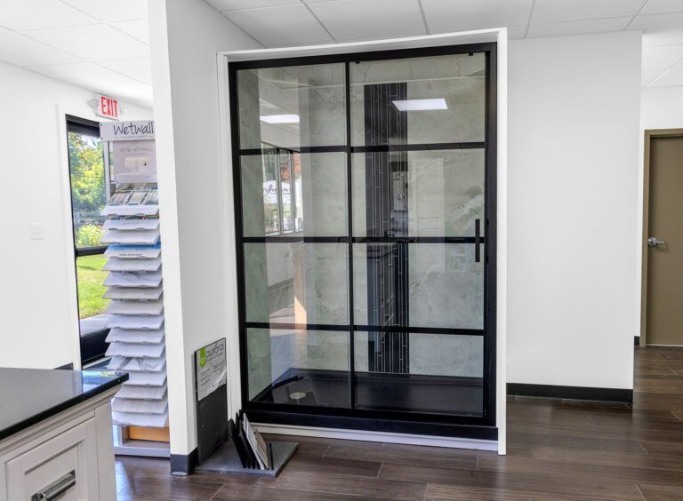 Glass phone booth in a bright office lobby with white walls and wood flooring
