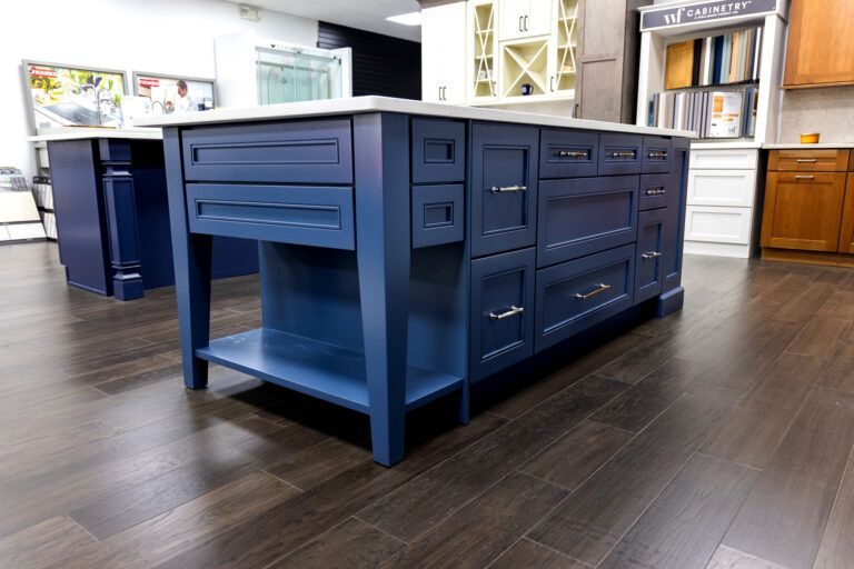 Navy blue kitchen island with drawers and shelves in a bright modern kitchen showroom