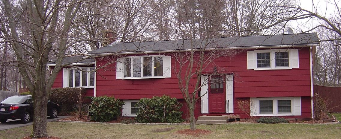 A red house with a black car parked in front of it.