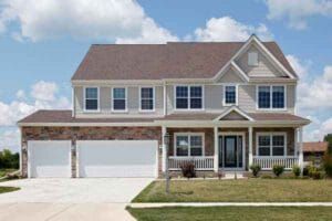 Two-story house with a brick facade, gray siding, white garage doors, and a front porch.