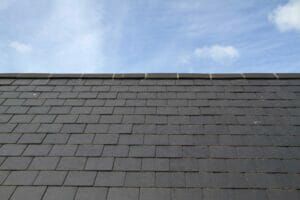 Dark gray slate roof against a blue sky with white clouds.