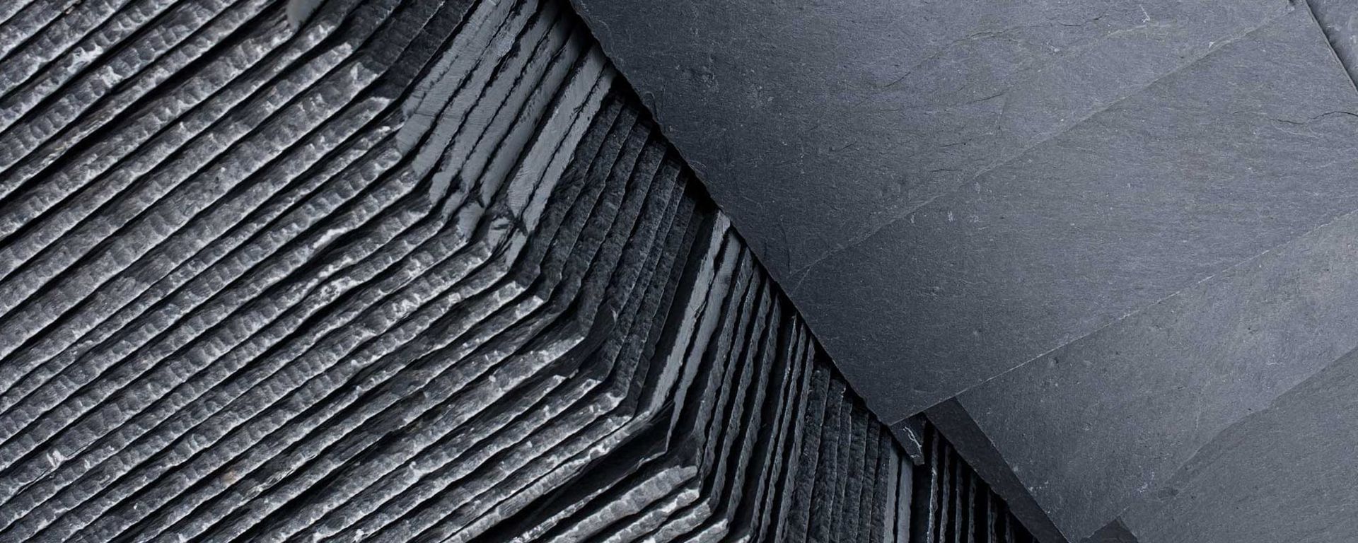 Close-up of gray slate tiles arranged in layers, with a smooth, flat surface on the upper right.