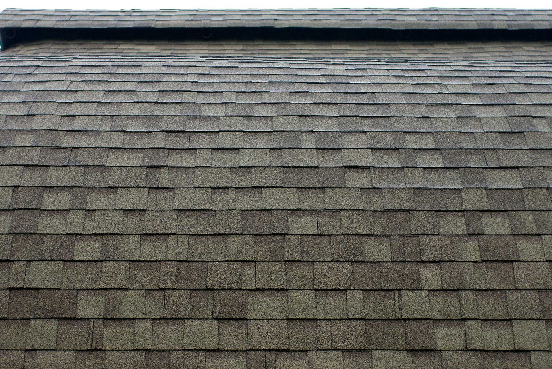 Close-up of a shingled roof with overlapping, rectangular brown shingles.