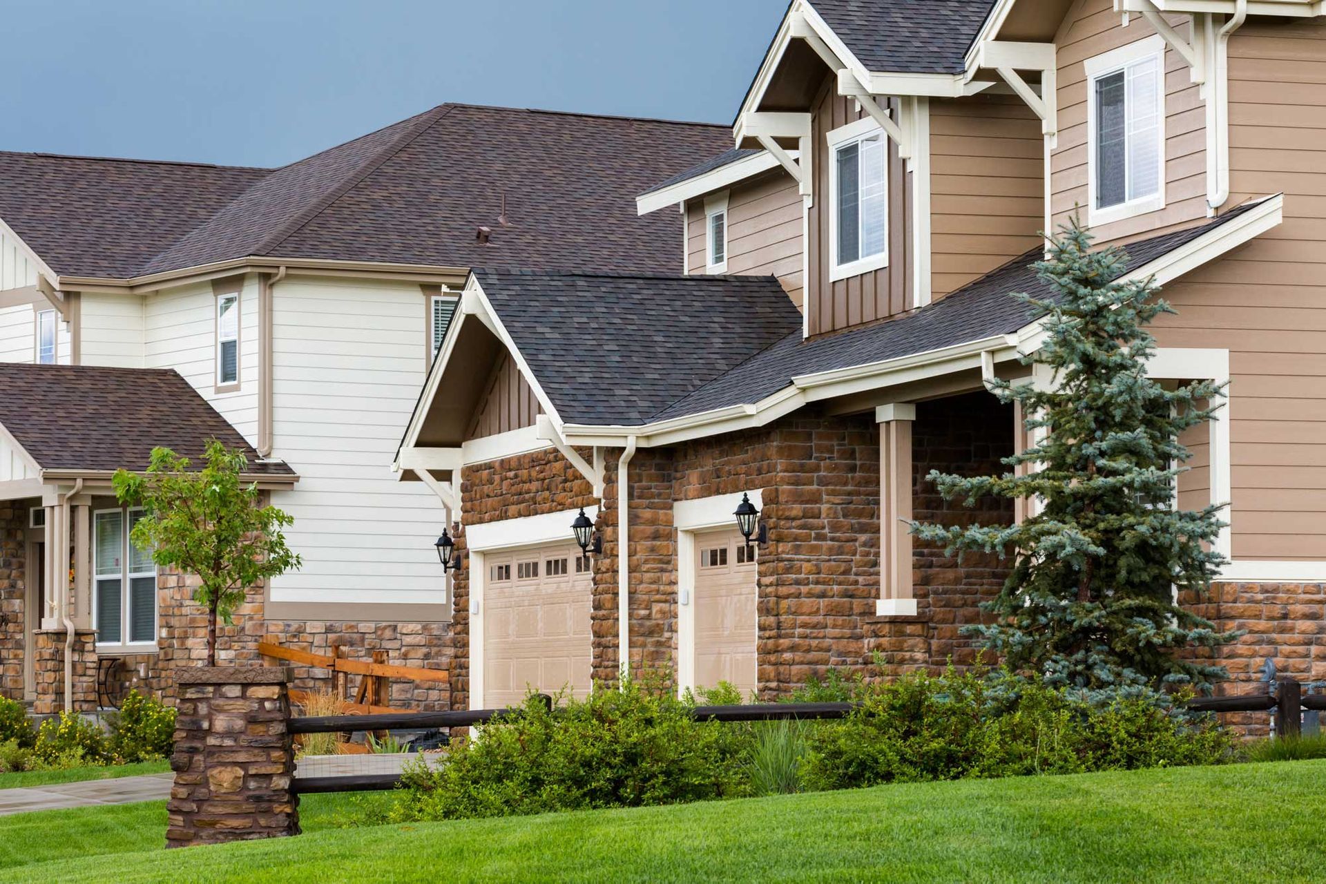Houses with brown and beige siding, a garage, and a green lawn.