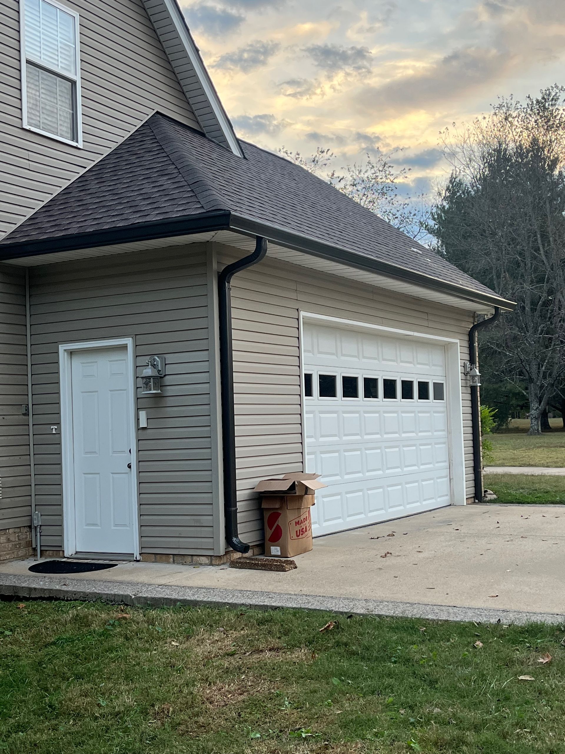 House exterior with white garage door, gray siding, and a small side entrance under a dark shingled roof.