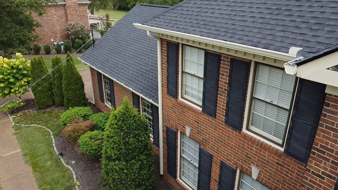 Brick apartment building with dark shutters and a landscaped walkway after rain
