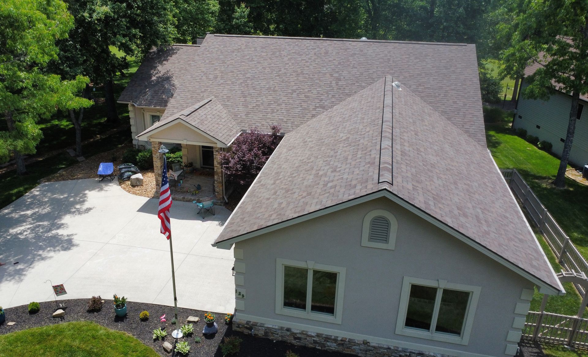 Aerial view of a suburban house with a front driveway, landscaped yard, and American flag.