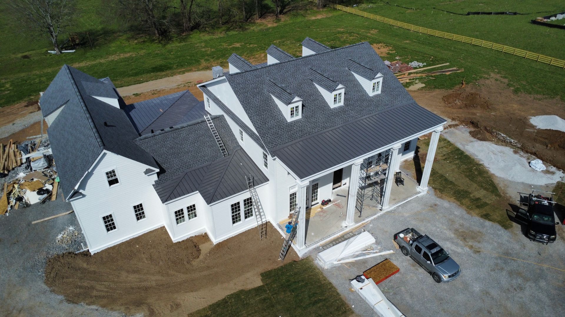 Aerial view of a large white house with a dark roof and driveway in a rural area.