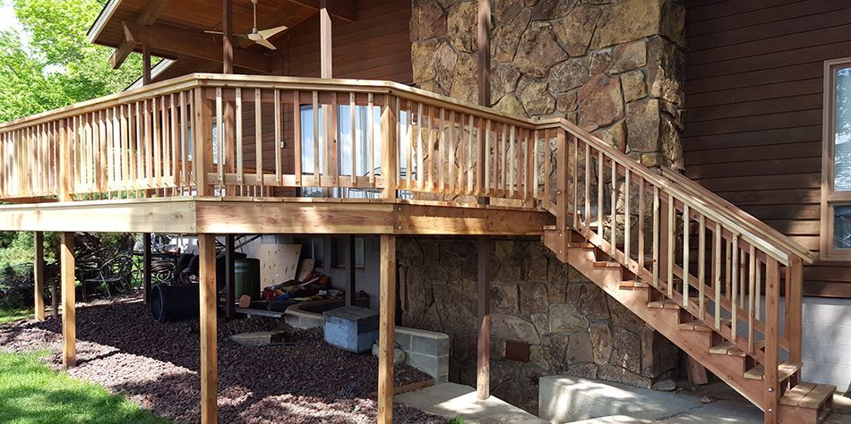 Wooden porch and staircase on a rustic elevated cabin with stone foundation.
