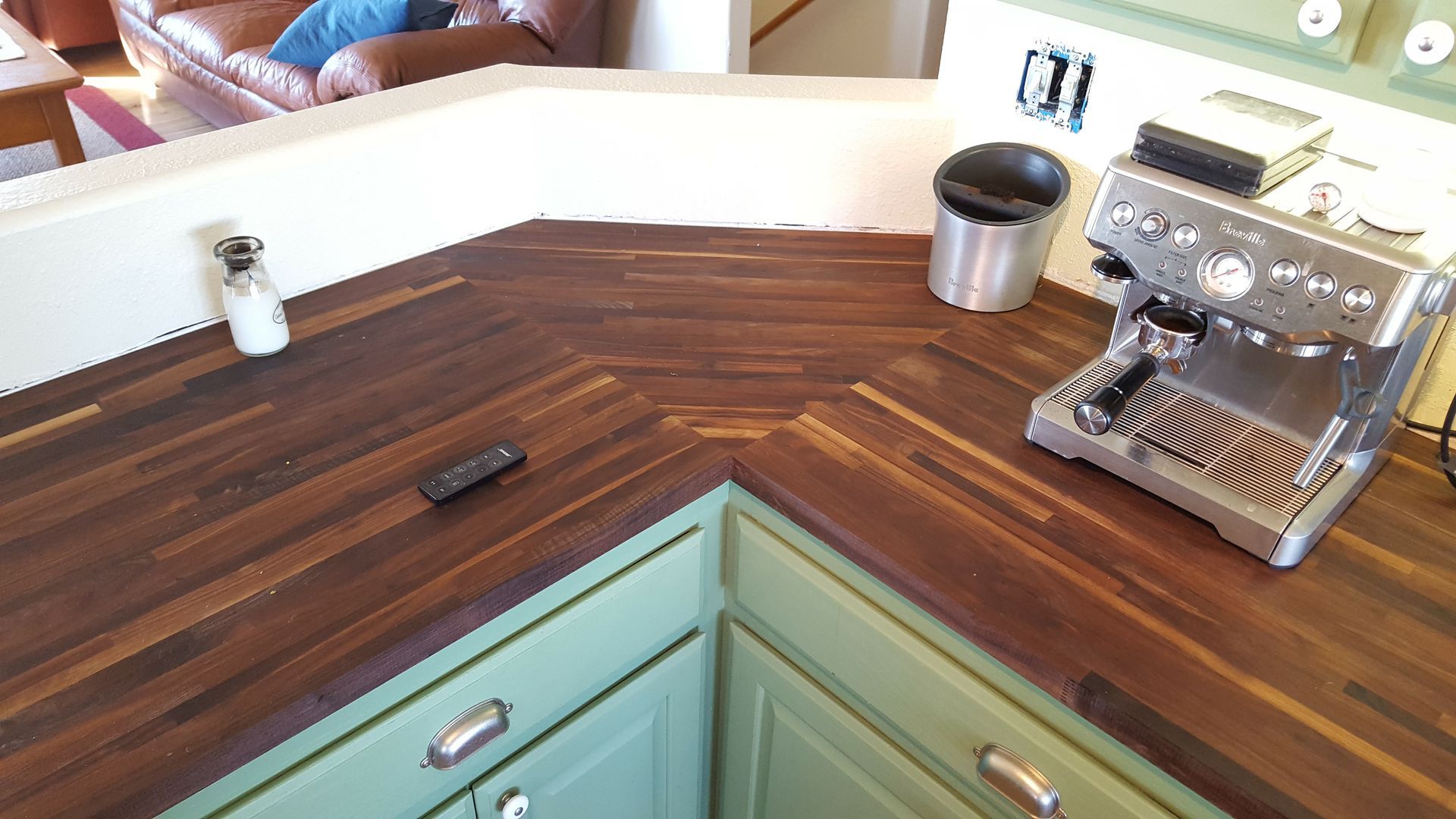 Corner kitchen countertop with wood butcher block, turquoise cabinets, espresso machine, and metal canister.