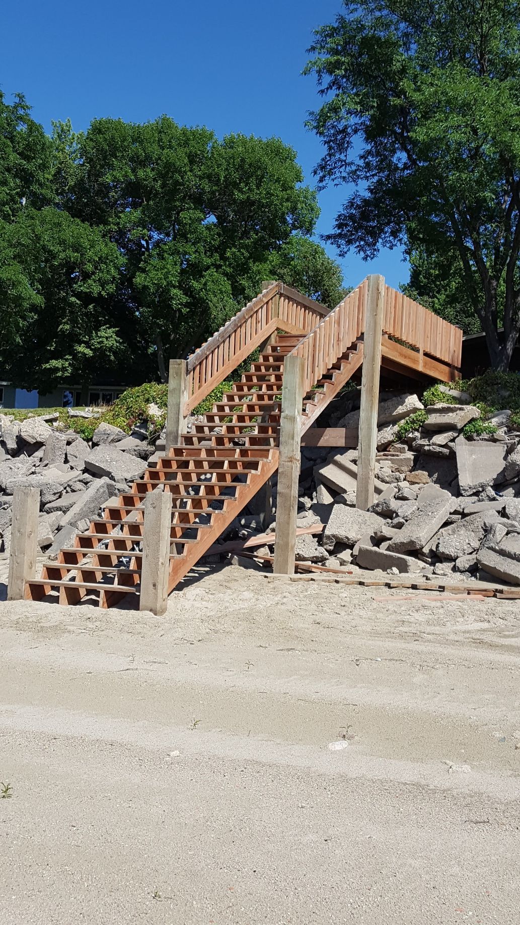 Wooden stairs and ramp built over a rocky slope, with trees in the background.