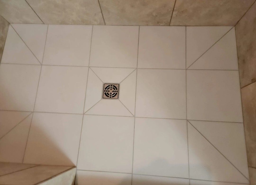 White tiled shower floor with a central drain.