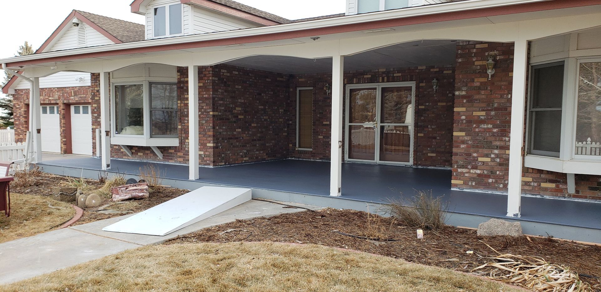 Brick house with a covered front porch, white columns, and a wheelchair ramp leading to the entrance.