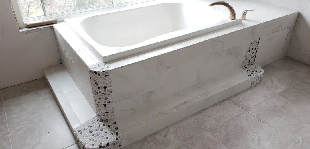 Marble walk-in bathtub with handrails and decorative cutouts in a bright bathroom.