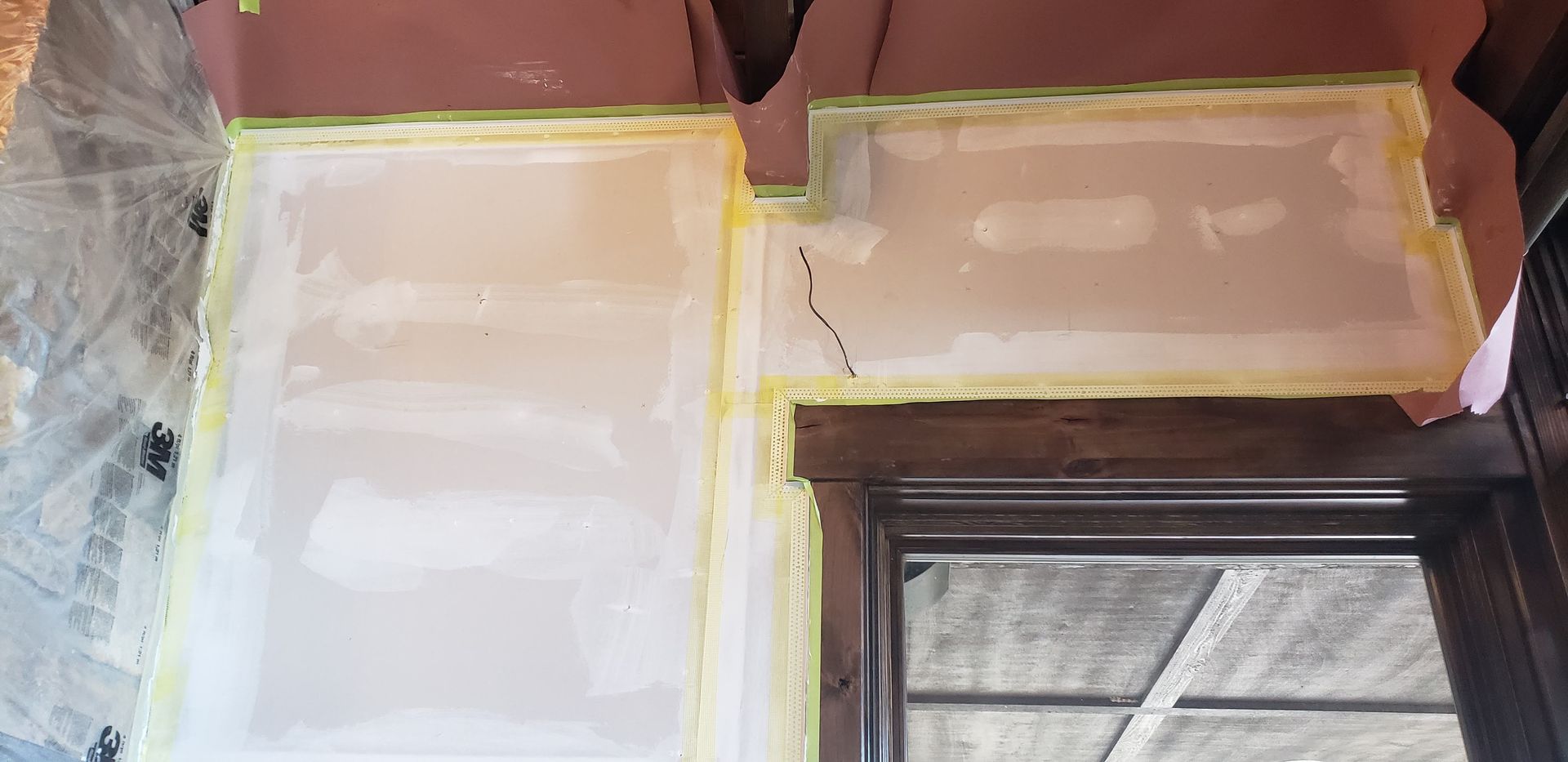 Freshly taped and plastered wall around a window during interior renovation.