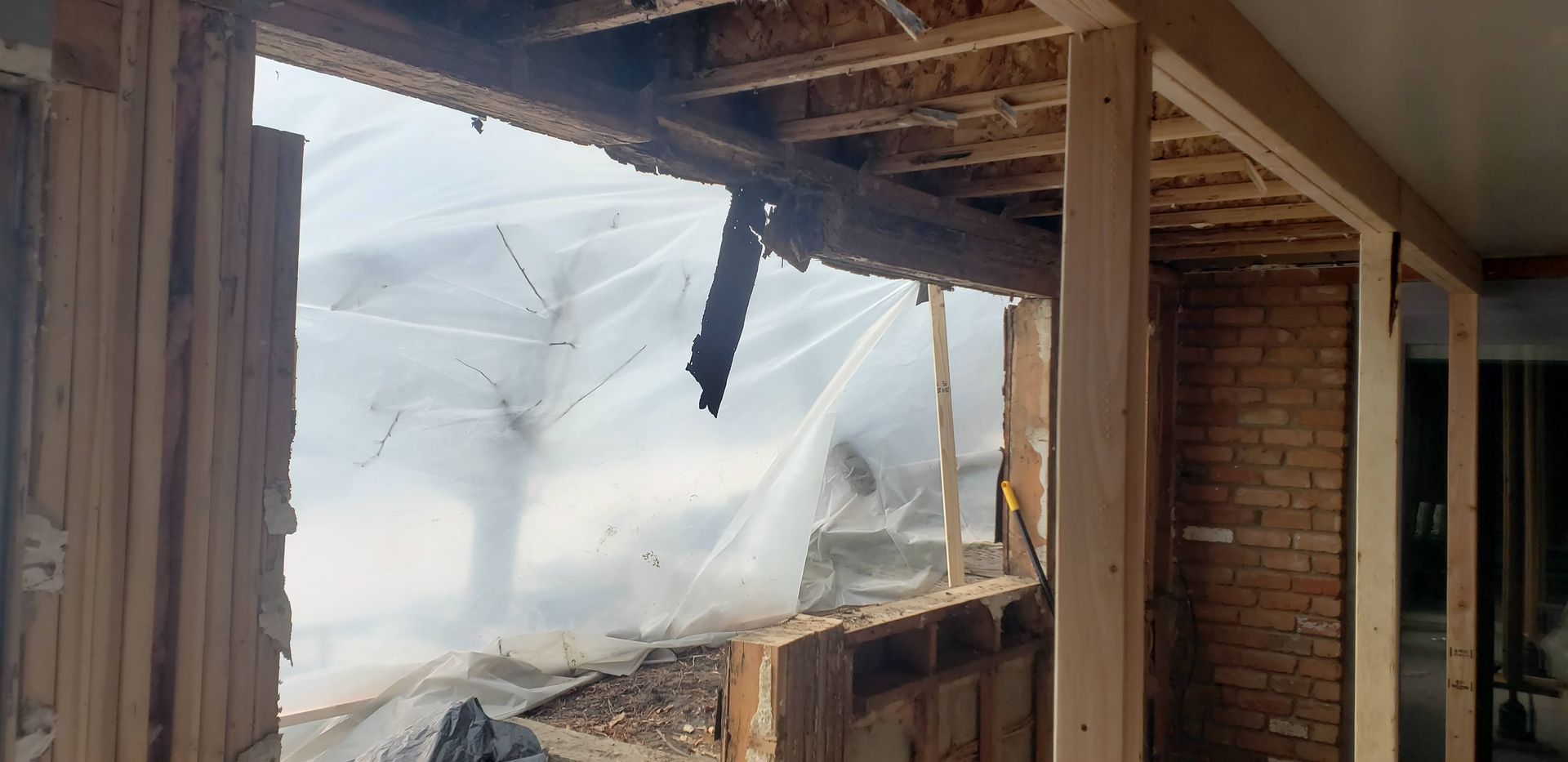 Fire-damaged room with collapsed wall and debris, smoke visible outside open frame.