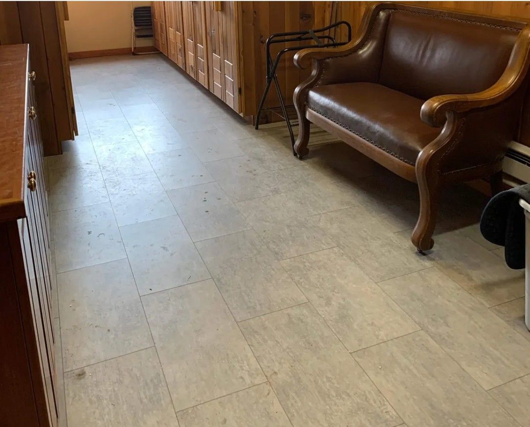 Wood-paneled hallway with tiled floor, cabinets, and a brown leather loveseat along the right wall.
