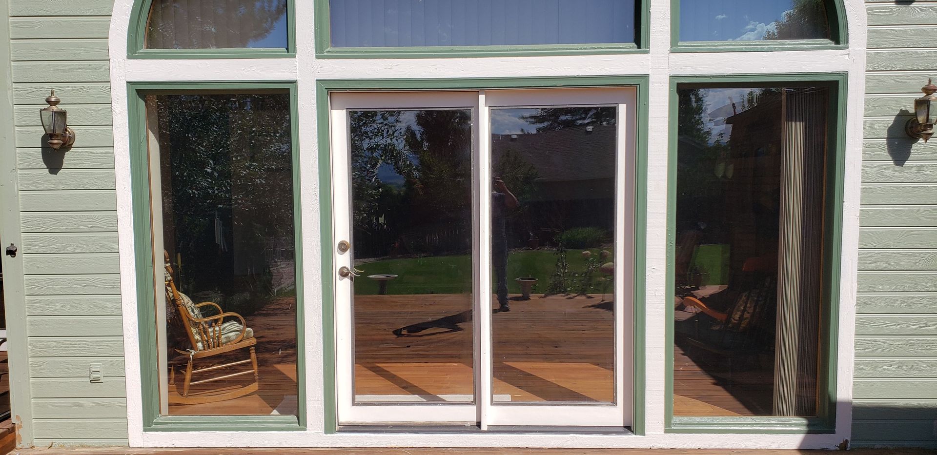 White house exterior with large arched windows and glass sliding doors on a porch.