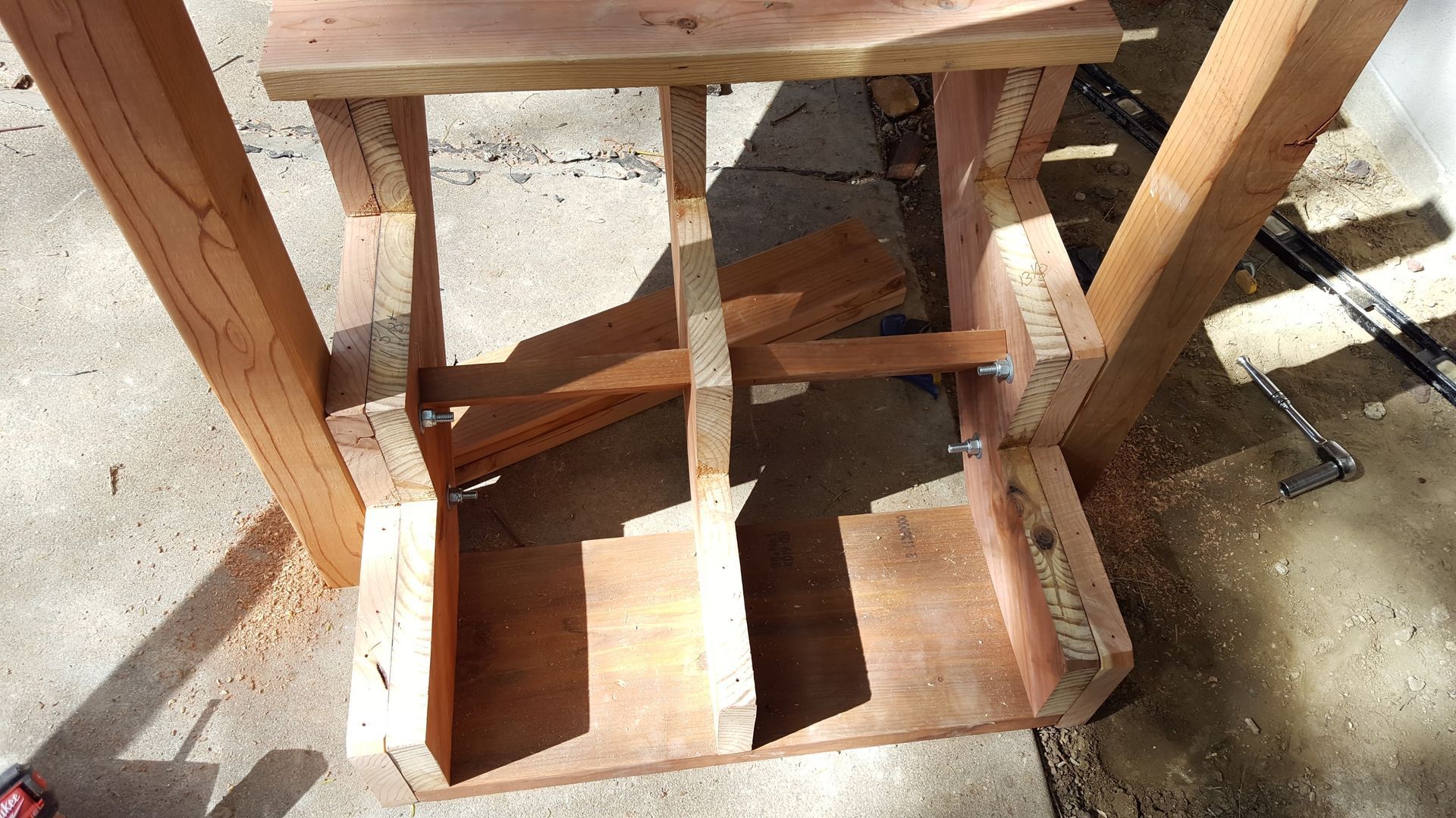 Wooden bench with a cutout and small box-like opening on a sunlit concrete floor.