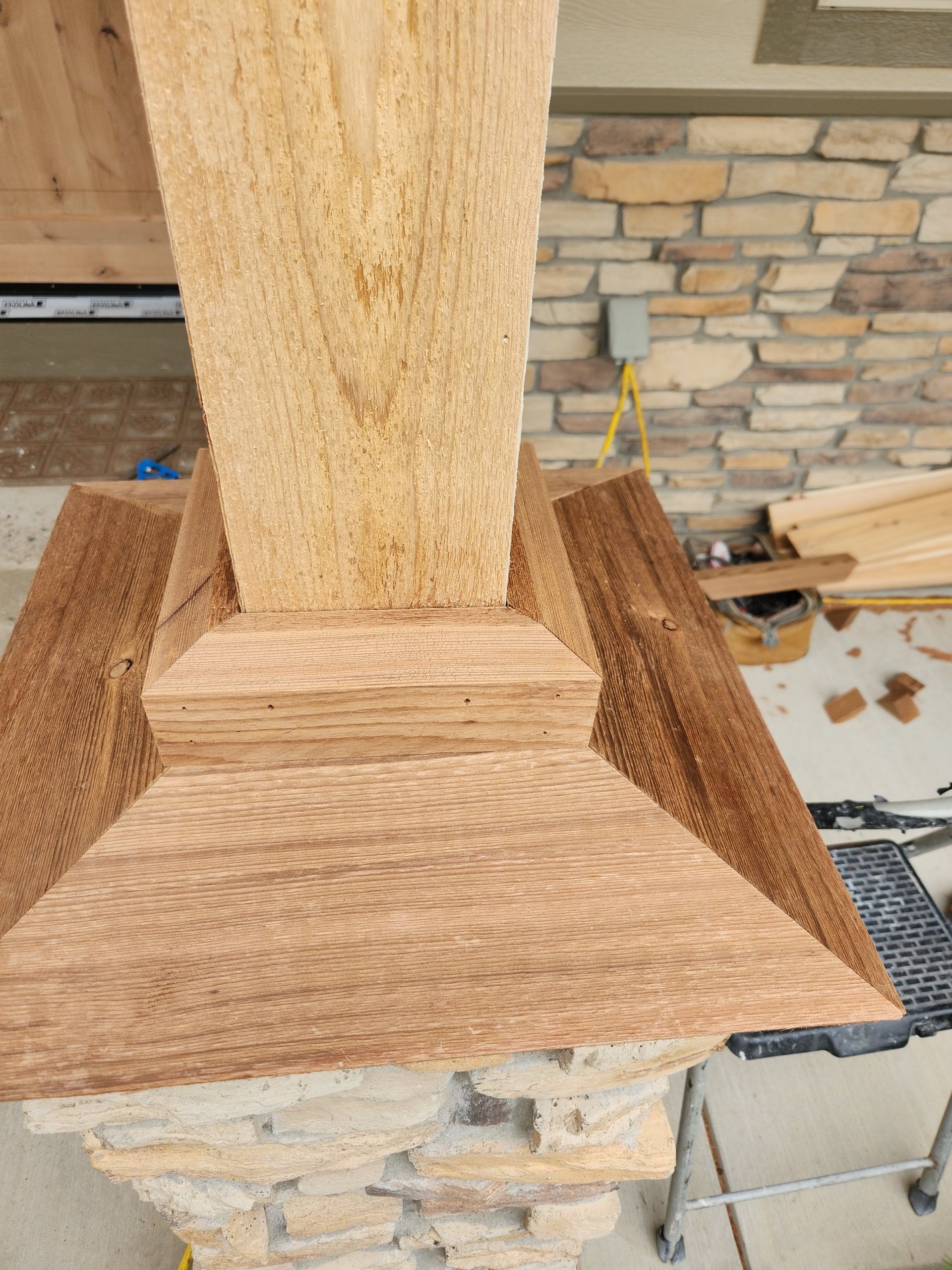 Close-up of a wooden post and base trim on a stone column during outdoor construction.