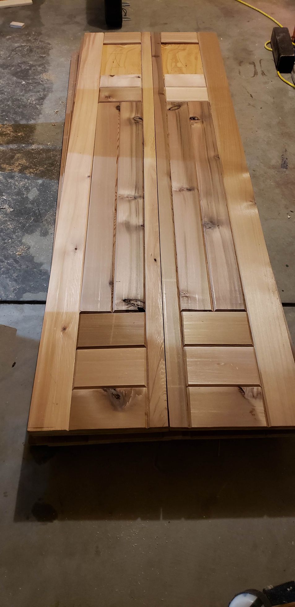 Stacked wooden pallets or boards laid lengthwise on a concrete floor in a workshop.