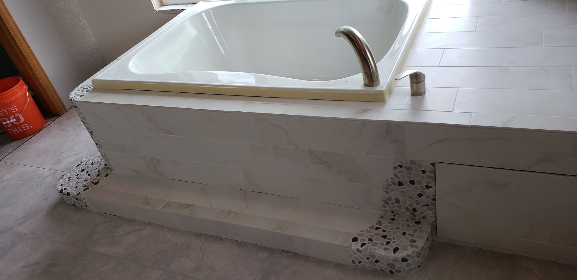 White step-through bathtub with built-in grab bar and side seat in a bathroom.