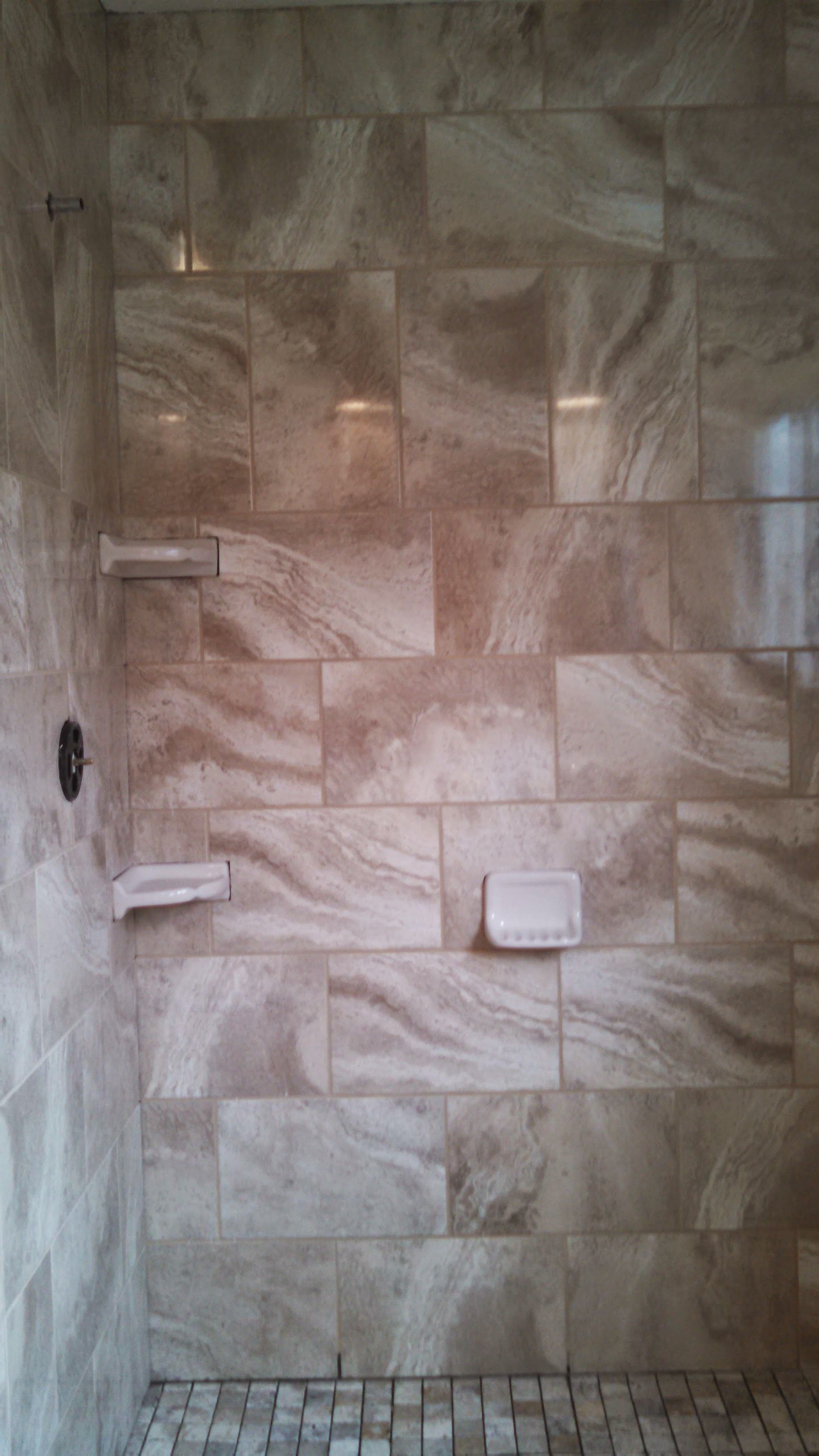 Tiled bathroom shower wall with built-in soap dishes and a small shelf.