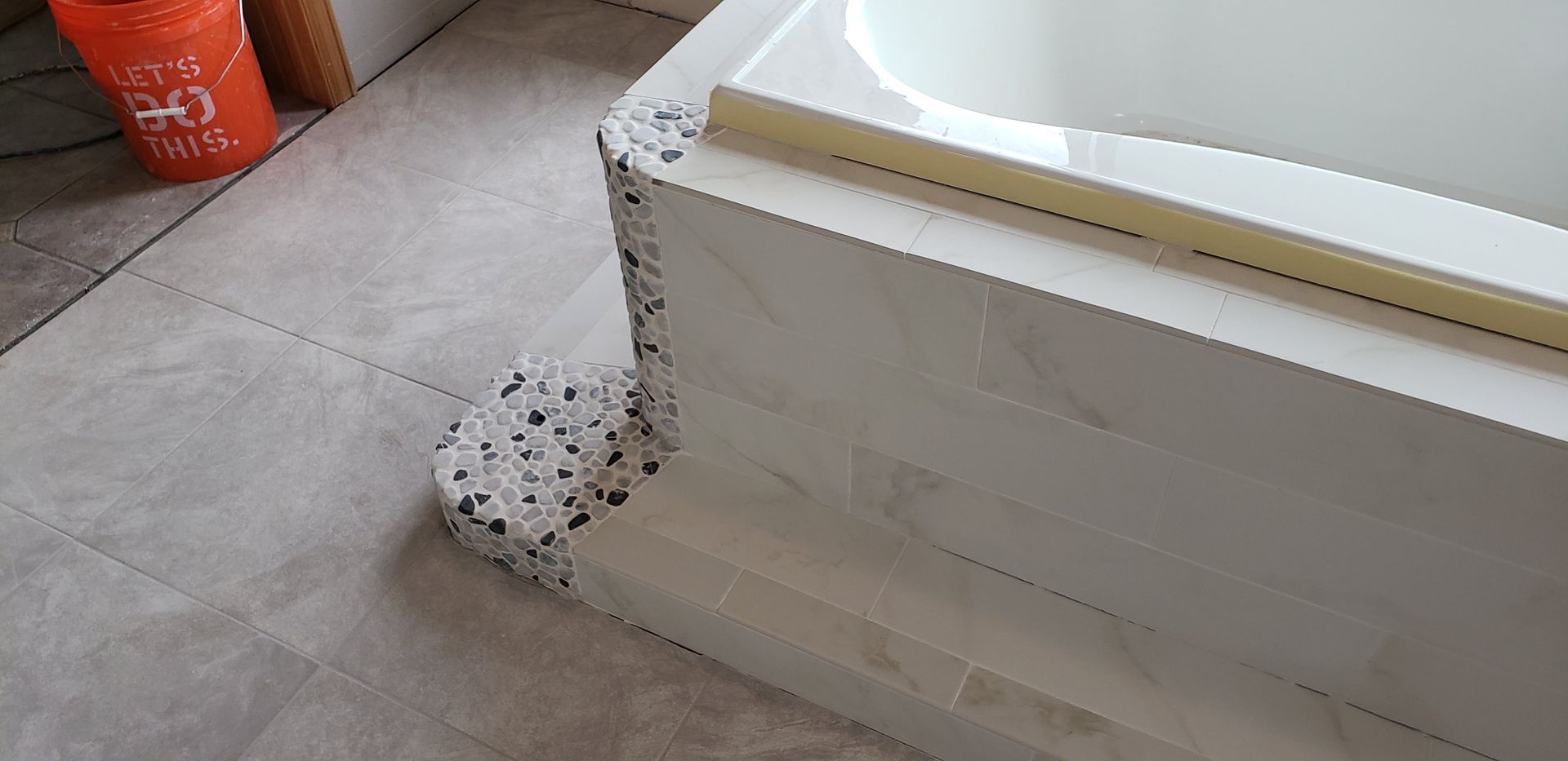 Spilled white foam or insulation at the base of a stair or ledge on a tiled floor.