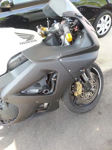 A black and white honda motorcycle is parked next to a black car.