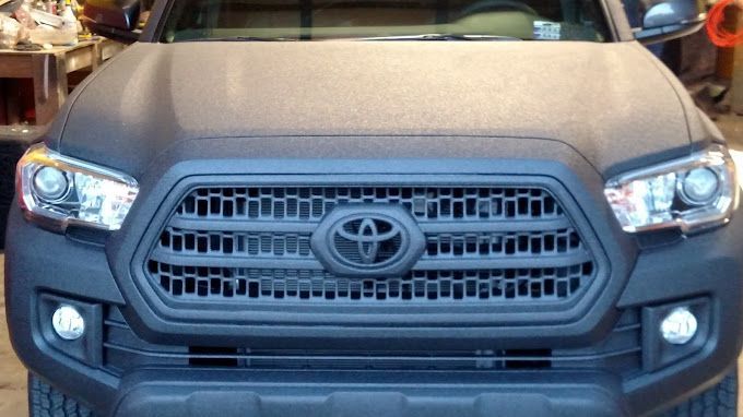 A black toyota tacoma truck is parked in a garage.