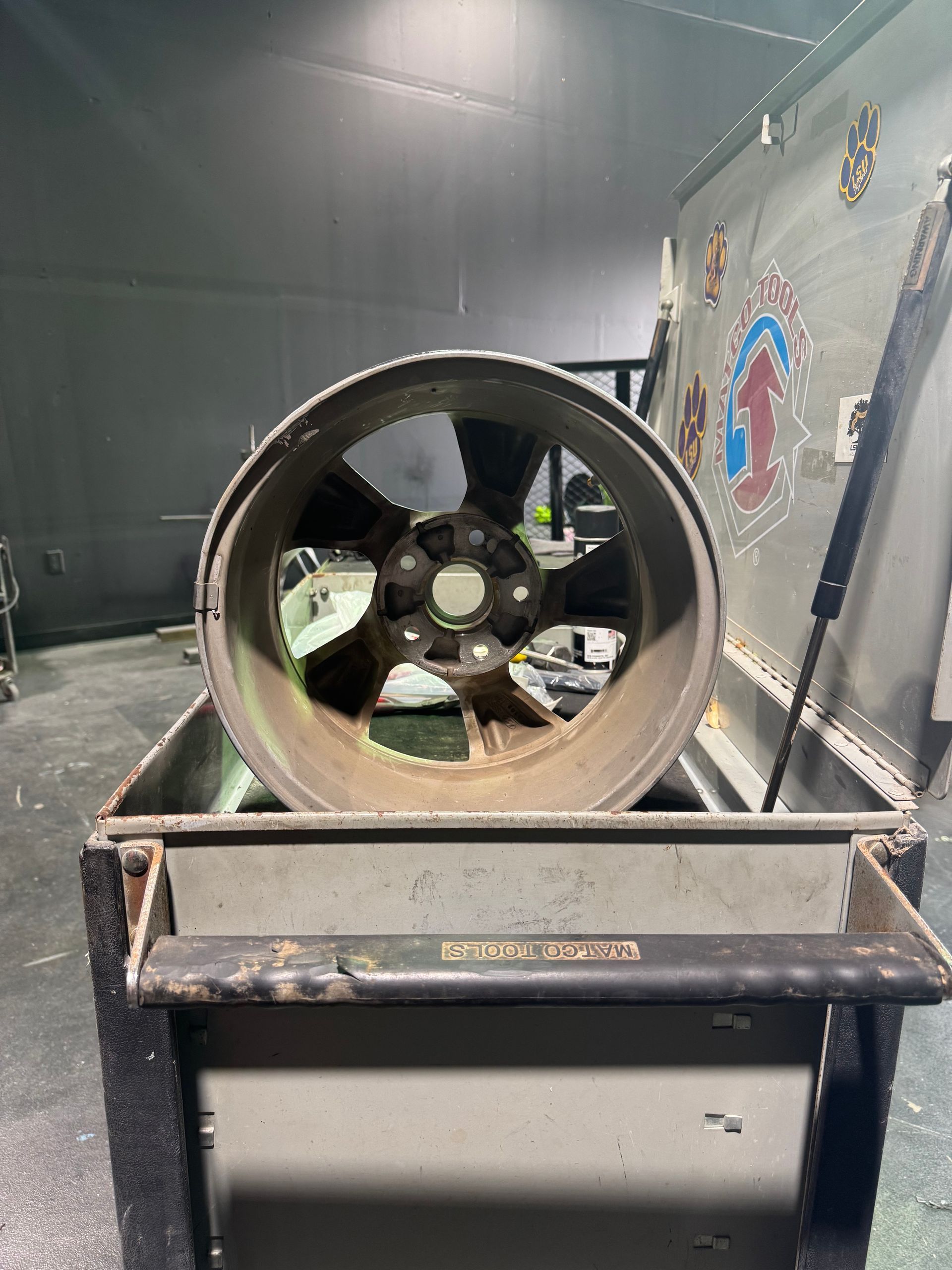 A wheel is sitting on top of a metal box in a garage.