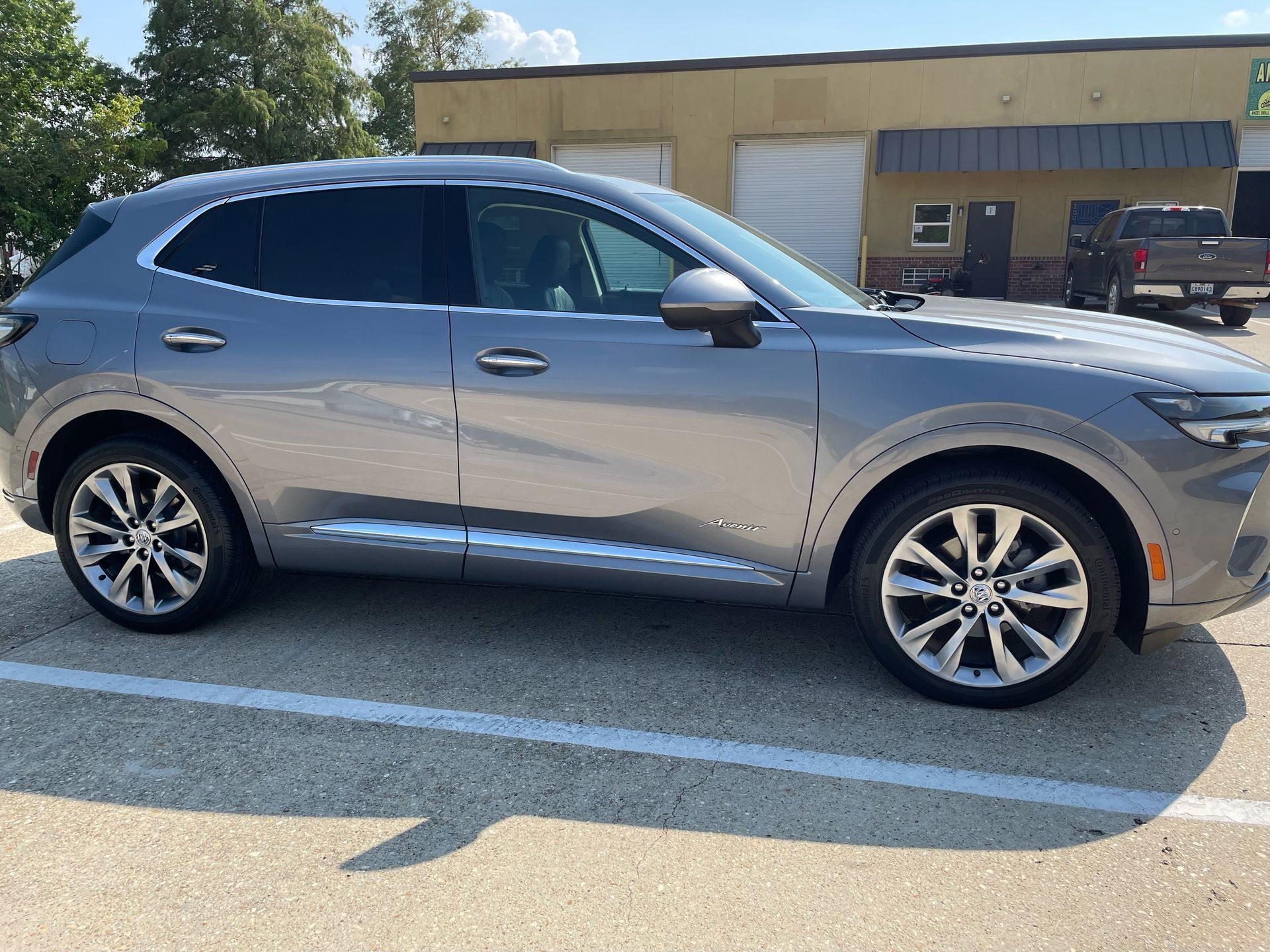 A silver car is parked in a parking lot in front of a building.