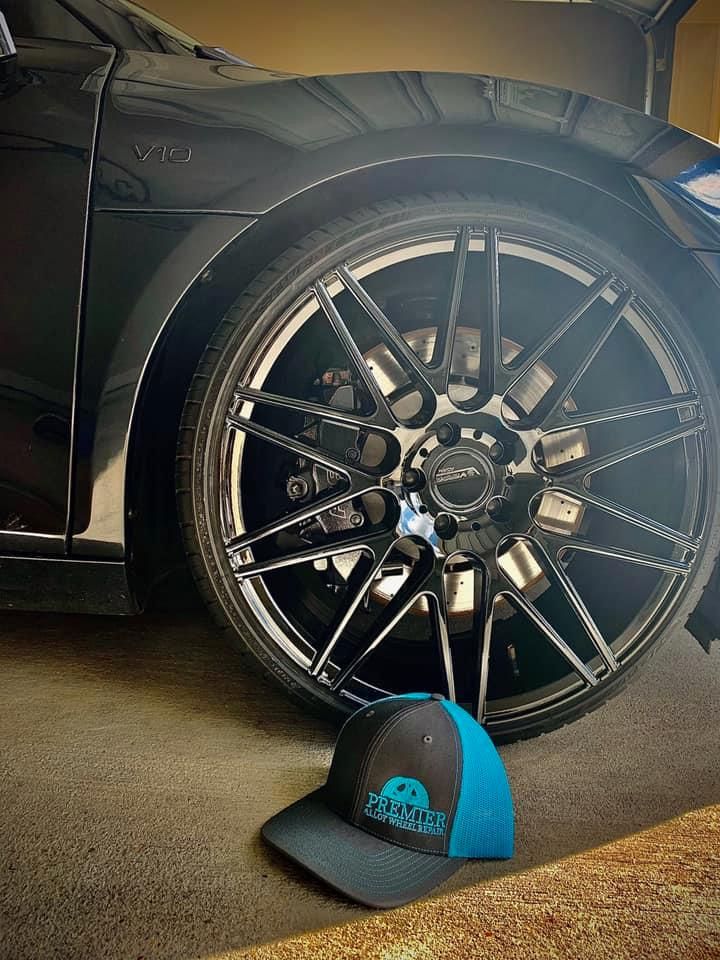 A black car is parked in a garage next to a blue hat.