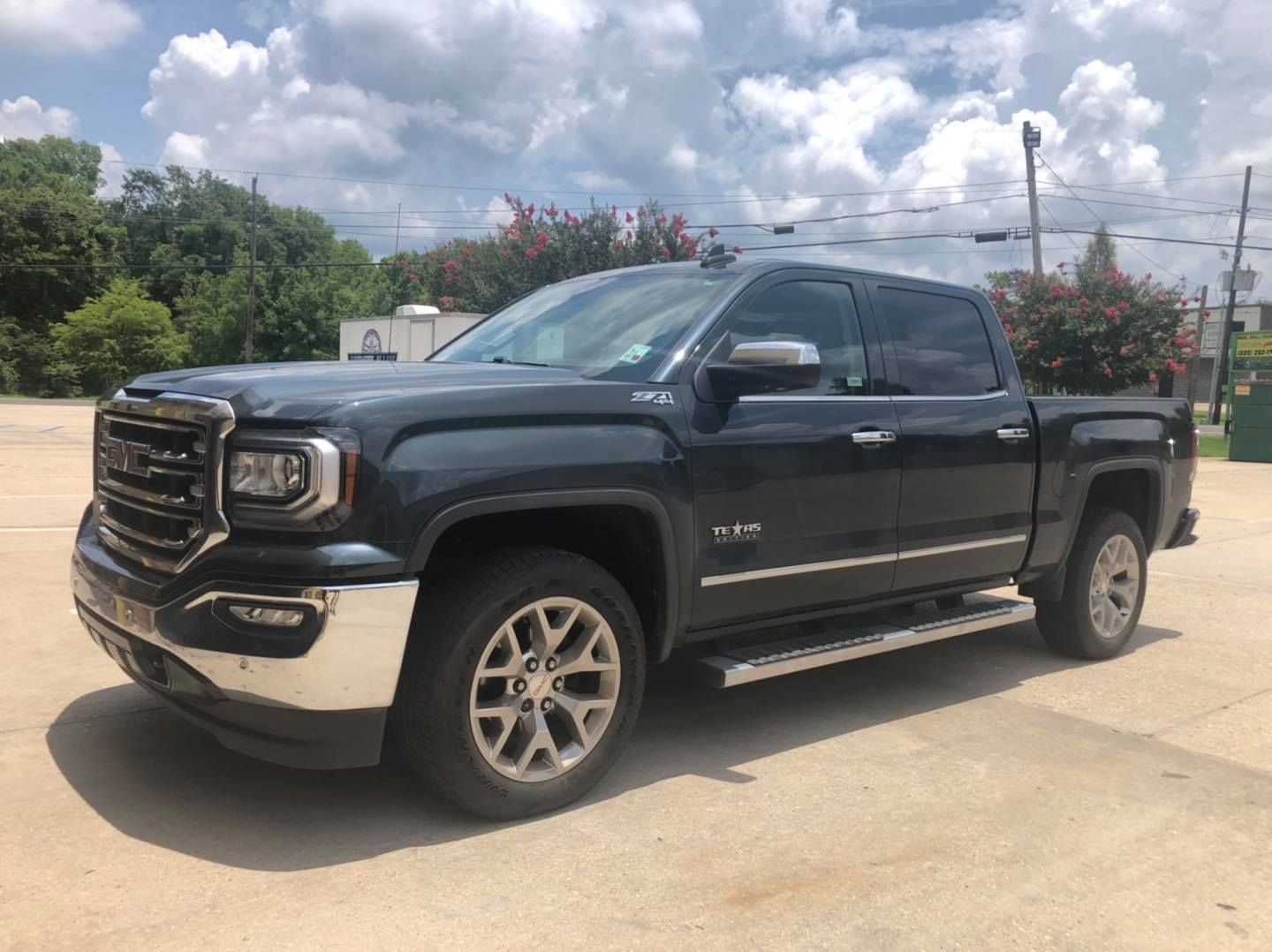 A blue gmc sierra pickup truck is parked in a parking lot.