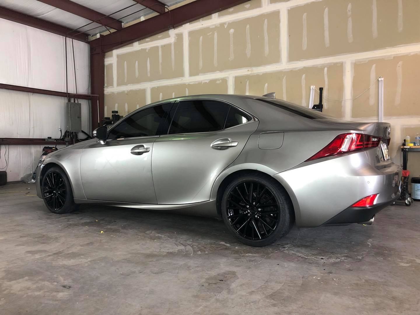 A silver car is parked in a garage with black wheels.