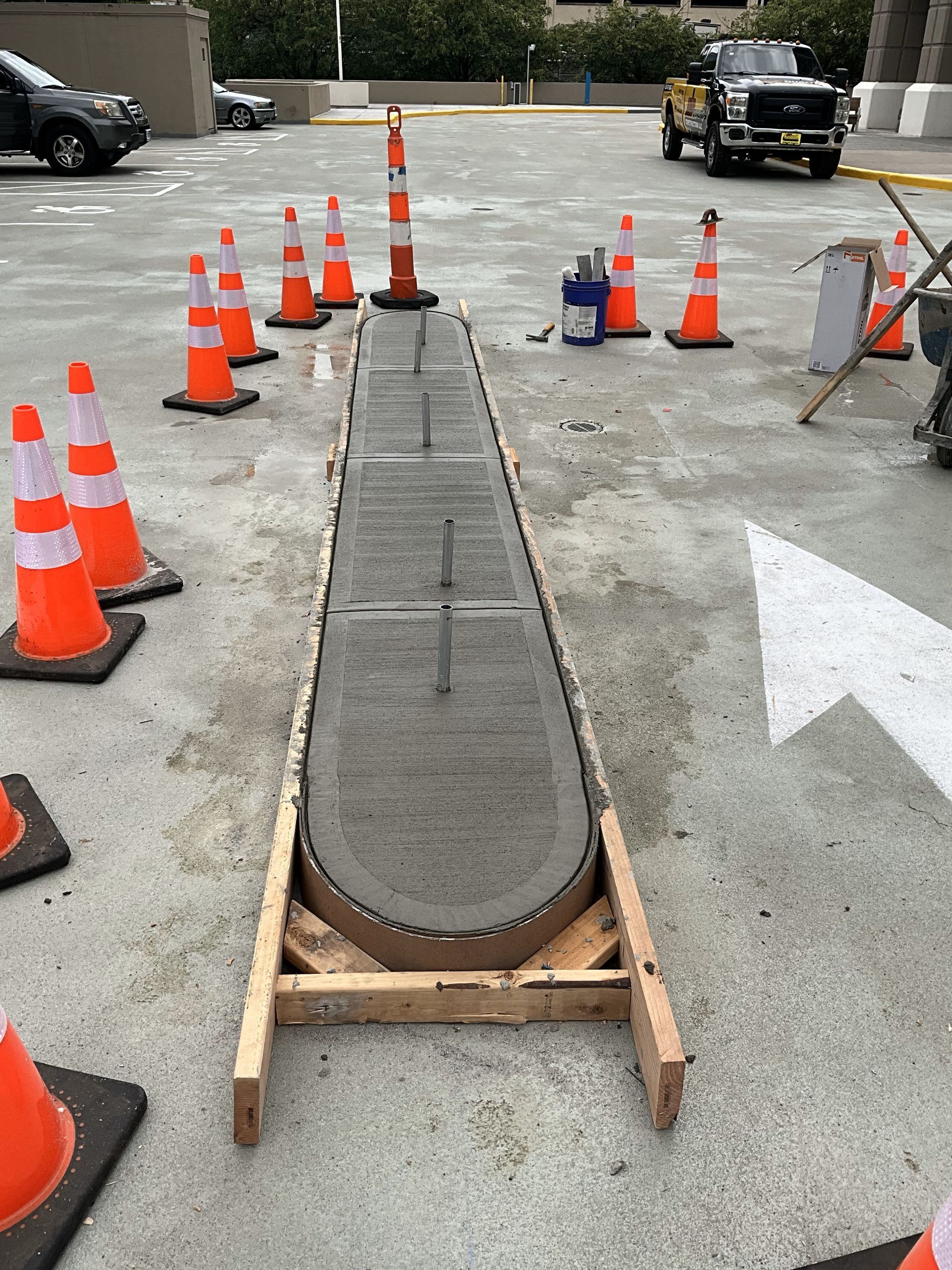 A row of orange and white traffic cones are lined up in a parking lot.