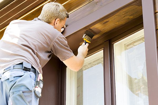 A man is painting a window frame with a brush.