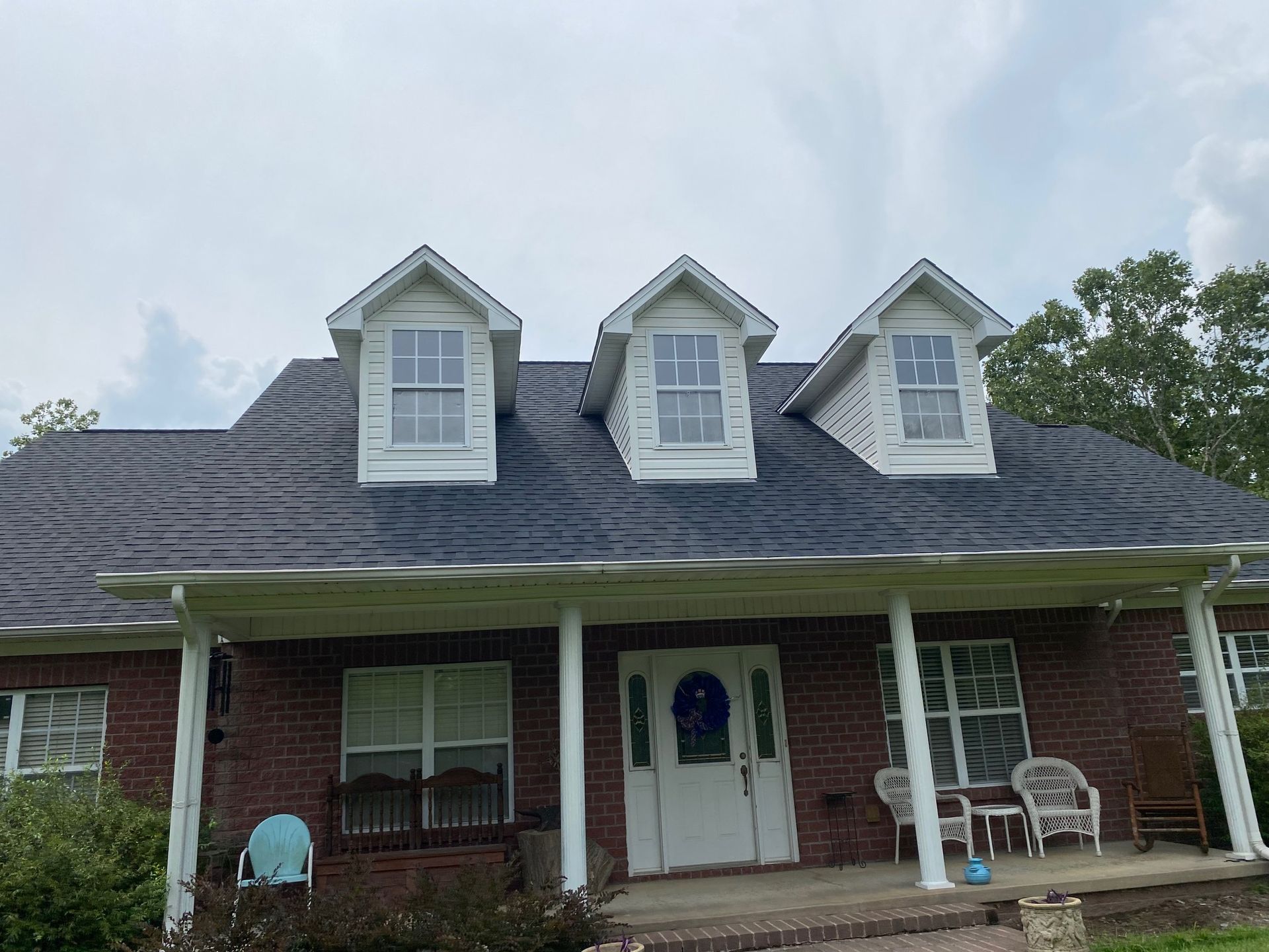 A large brick house with a porch and a blue roof.