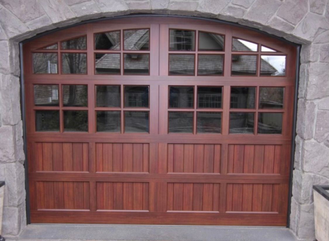 A wooden garage door with a stone wall behind it