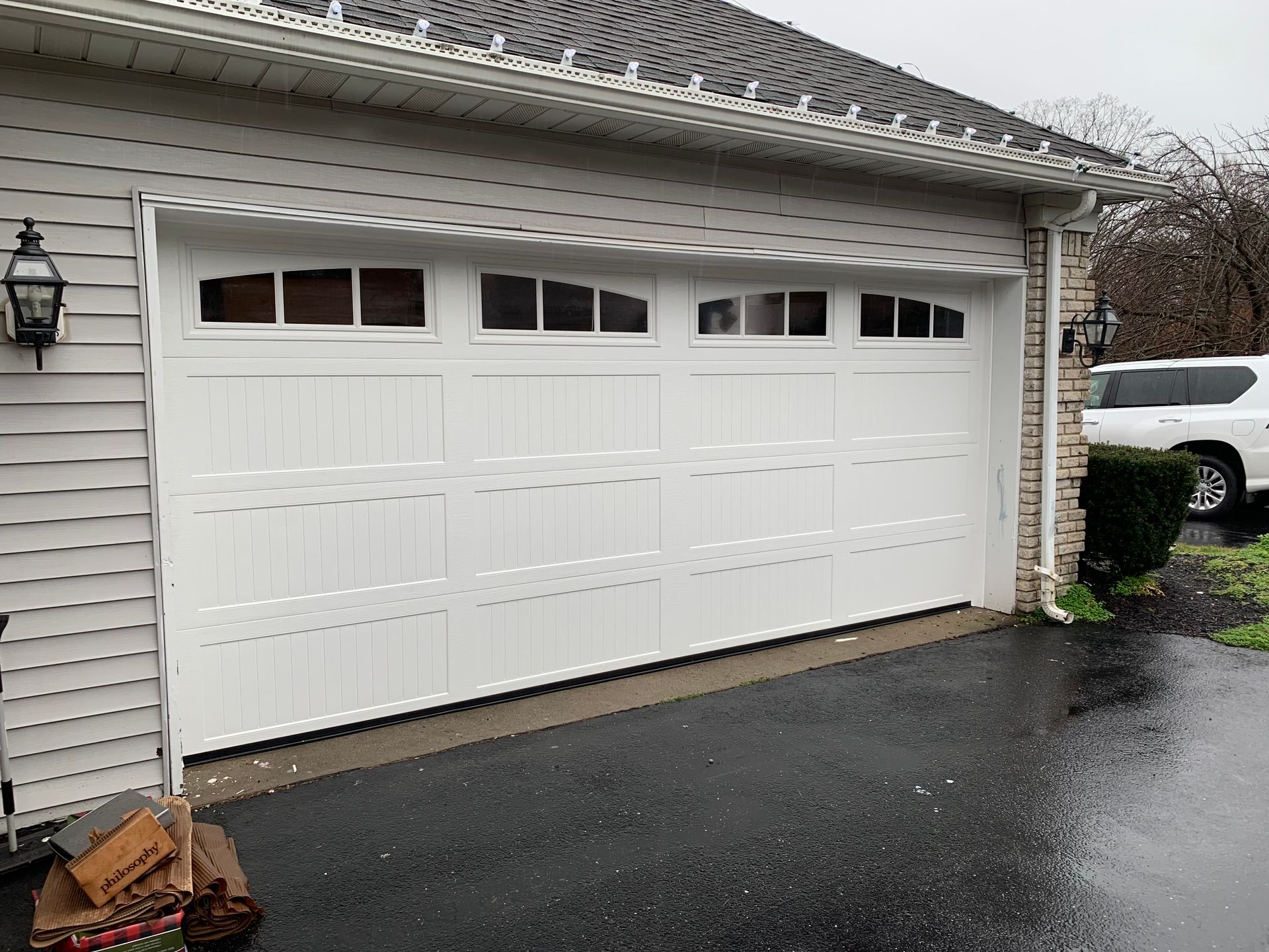 A white garage door is open and a car is parked in front of it.