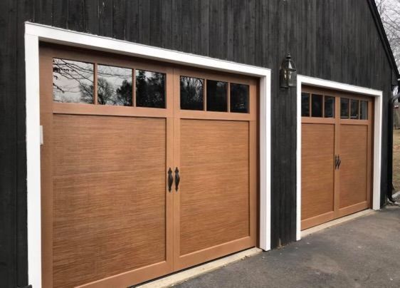 Three wooden garage doors are on a black building.