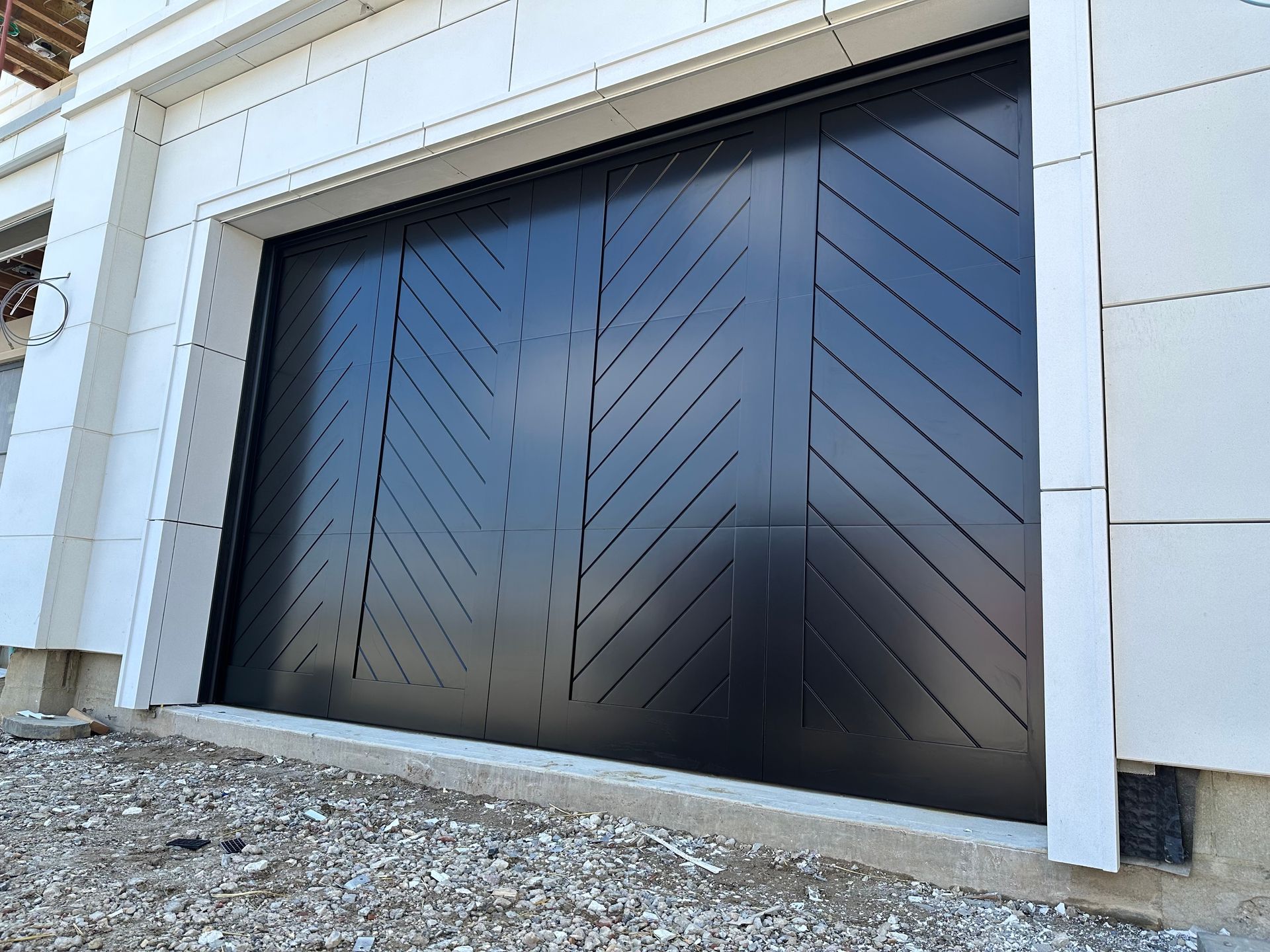 A black garage door with a chevron pattern on it is on the side of a building.